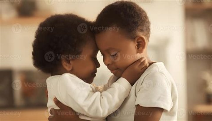 two young children hugging each other while sitting on a couch